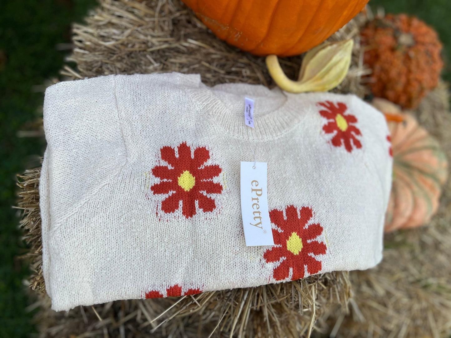 Relaxed fit boucle fabric floral knit cropped sweater is adorned w/ red and yellow flowers. Crew neck & long sleeves.