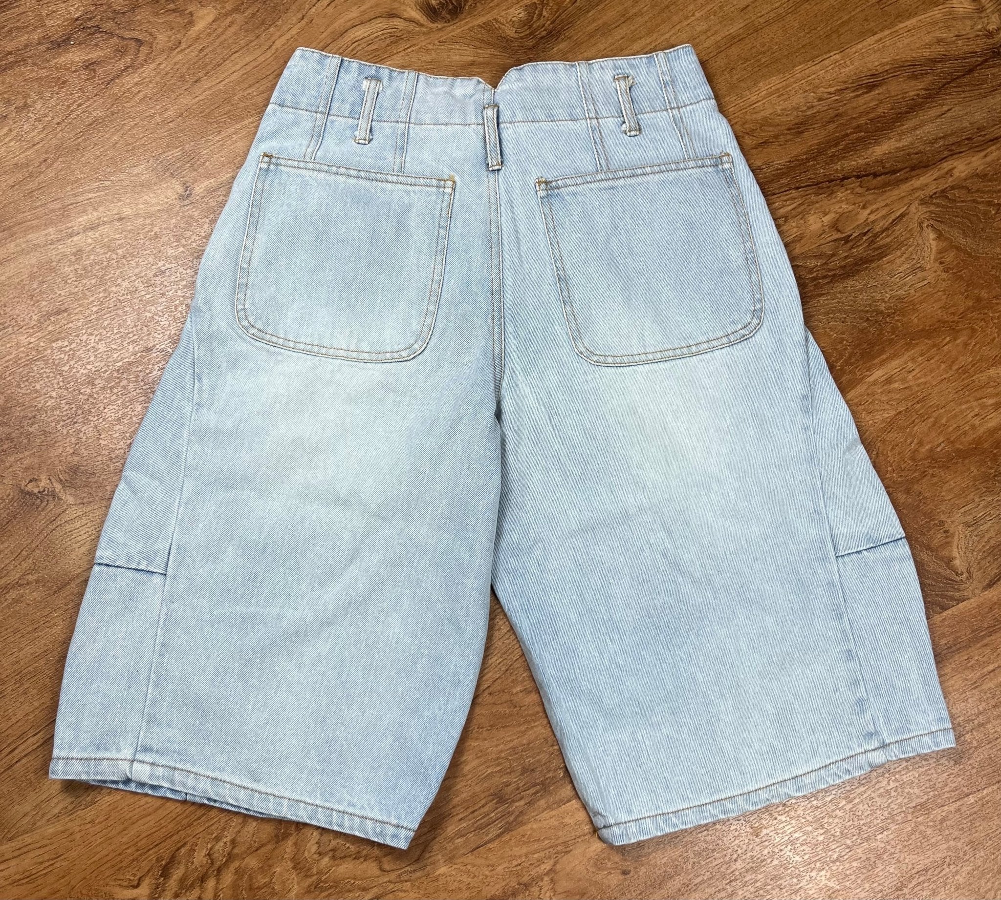 Blue B brand. These light wash cargo denim knee length shorts feature a mid-rise and exaggerated tapered slouchy fit.