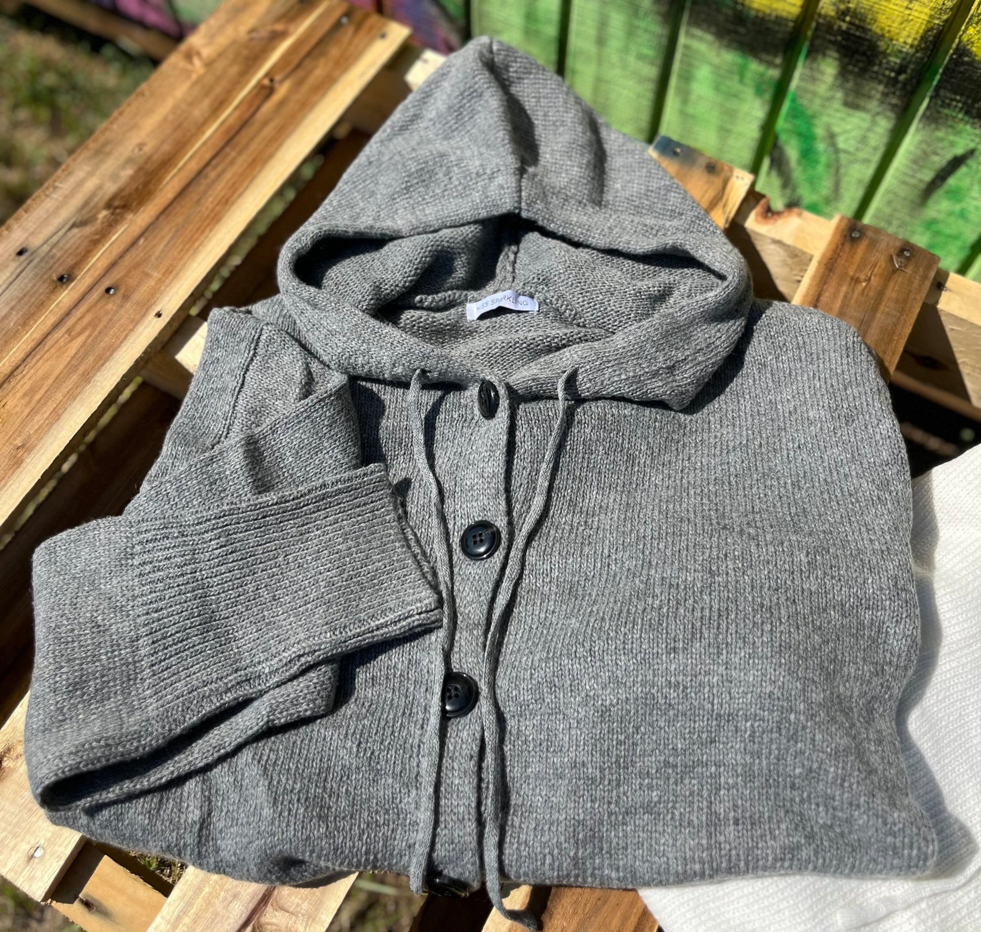 Button front hooded cardigan with adjustable drawstrings and ribbed cuffs is available in classic black, grey or off white.