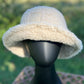 Hana brand. The C.C rubber patch bucket hat is 100% faux sherpa and is available in beige or classic black. One size. $20