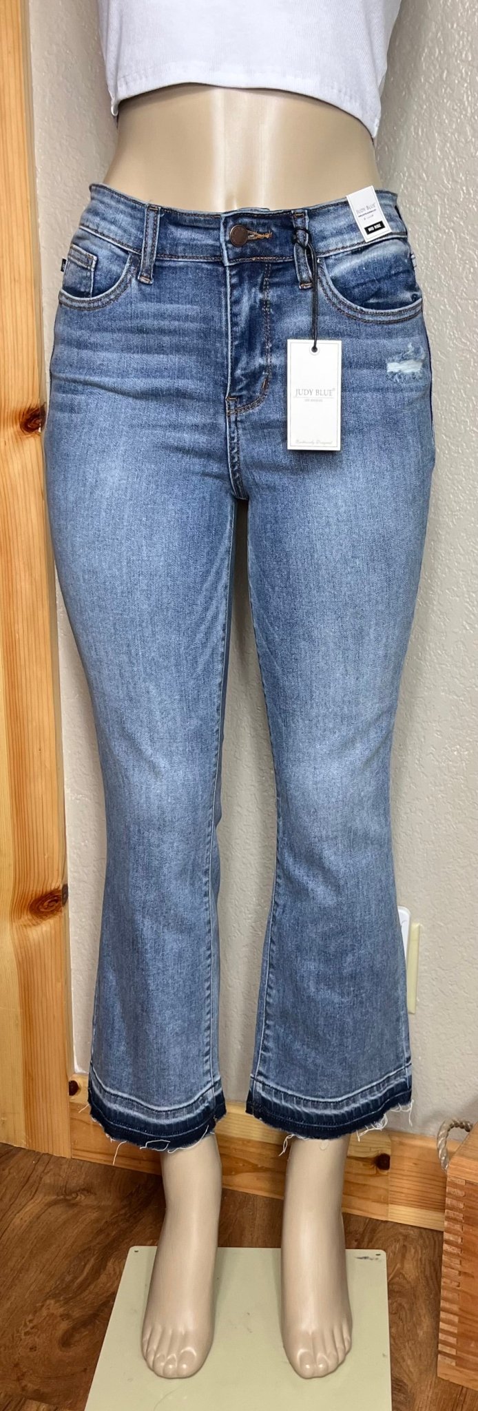 Judy Blue brand. Mid rise, release hem, cropped bootcut jean has front pocket distressed accent.