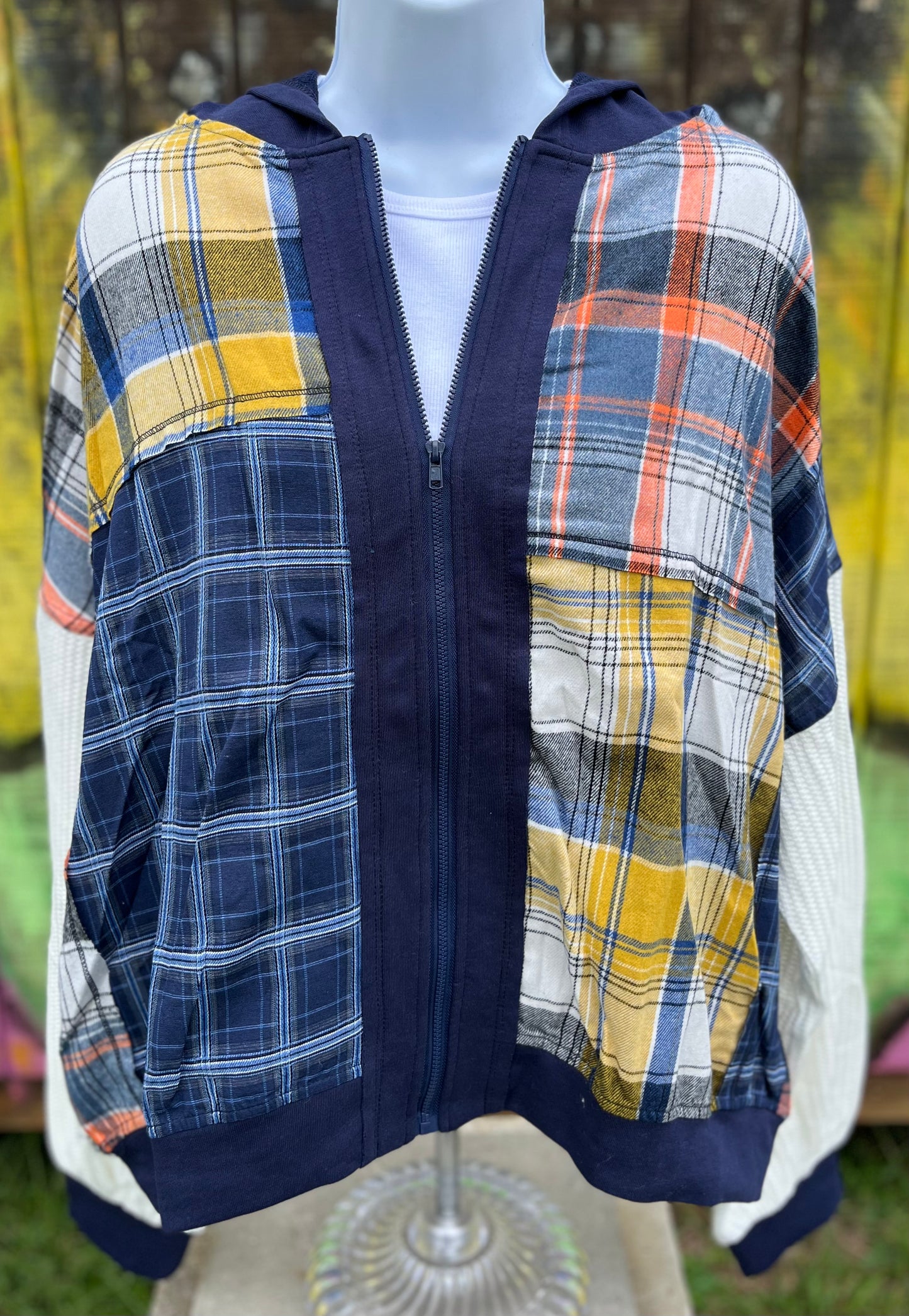 Features multicolored contrast patchwork flannel w/ waffle knit sleeves & banded navy opening w/ matching zipper & hood.