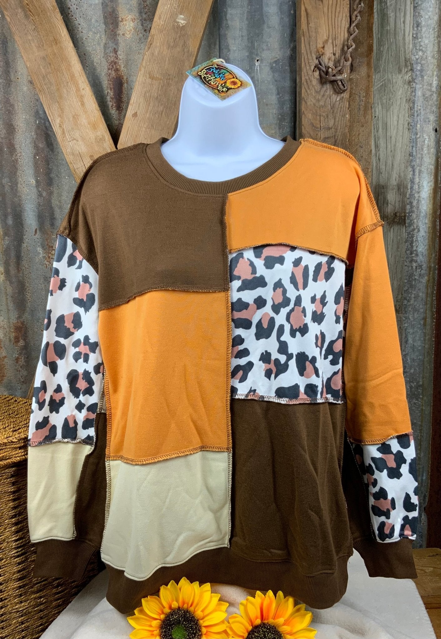 Color block sweatshirt features a combination of brown, orange cream and leopard with cuffed sleeves and exposed seams.