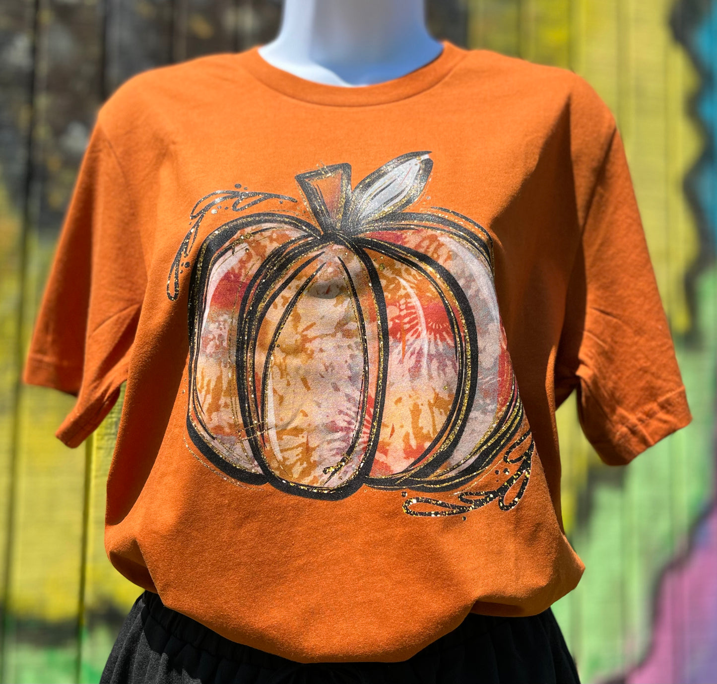 Southern Attitude Designs Inc brand. Soft Bella Canvas burnt orange/rust tee with tie dye pumpkin in autumn colors and simulated gold glitter. S, M, L, XL, 2X. $25