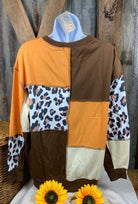 Color block sweatshirt features a combination of brown, orange cream and leopard with cuffed sleeves and exposed seams.