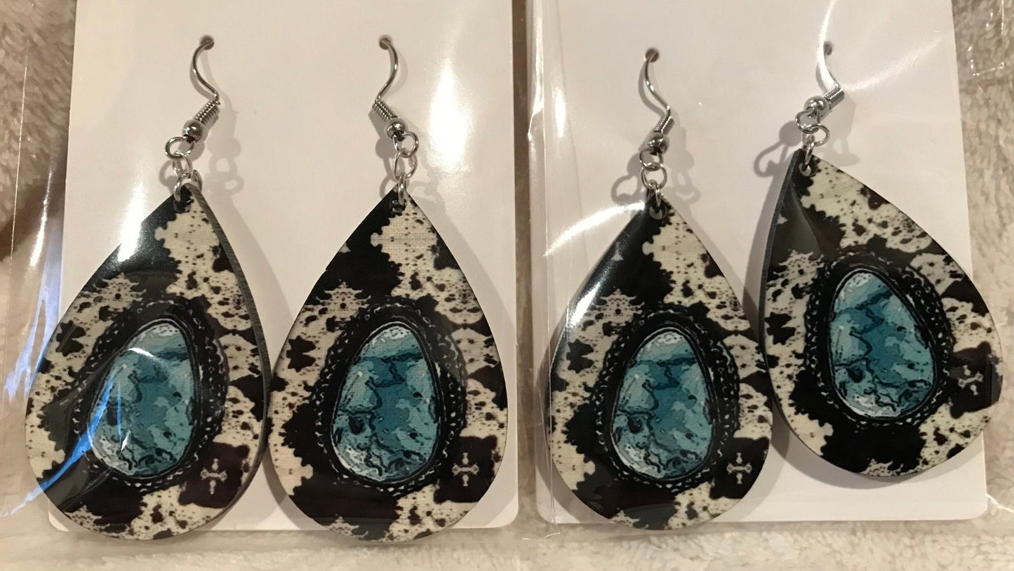 Earring Babe Boutique brand. Silver dangle, 2.5" hard material, simulated cow print with turquoise center. $7.25