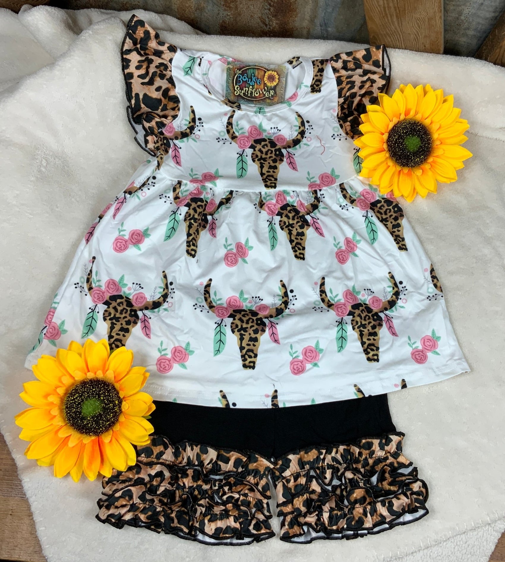 White top w/ leopard ruffled cap sleeves & leopard longhorn skull & pink flowers. Black shorts w/ leopard ruffle design.