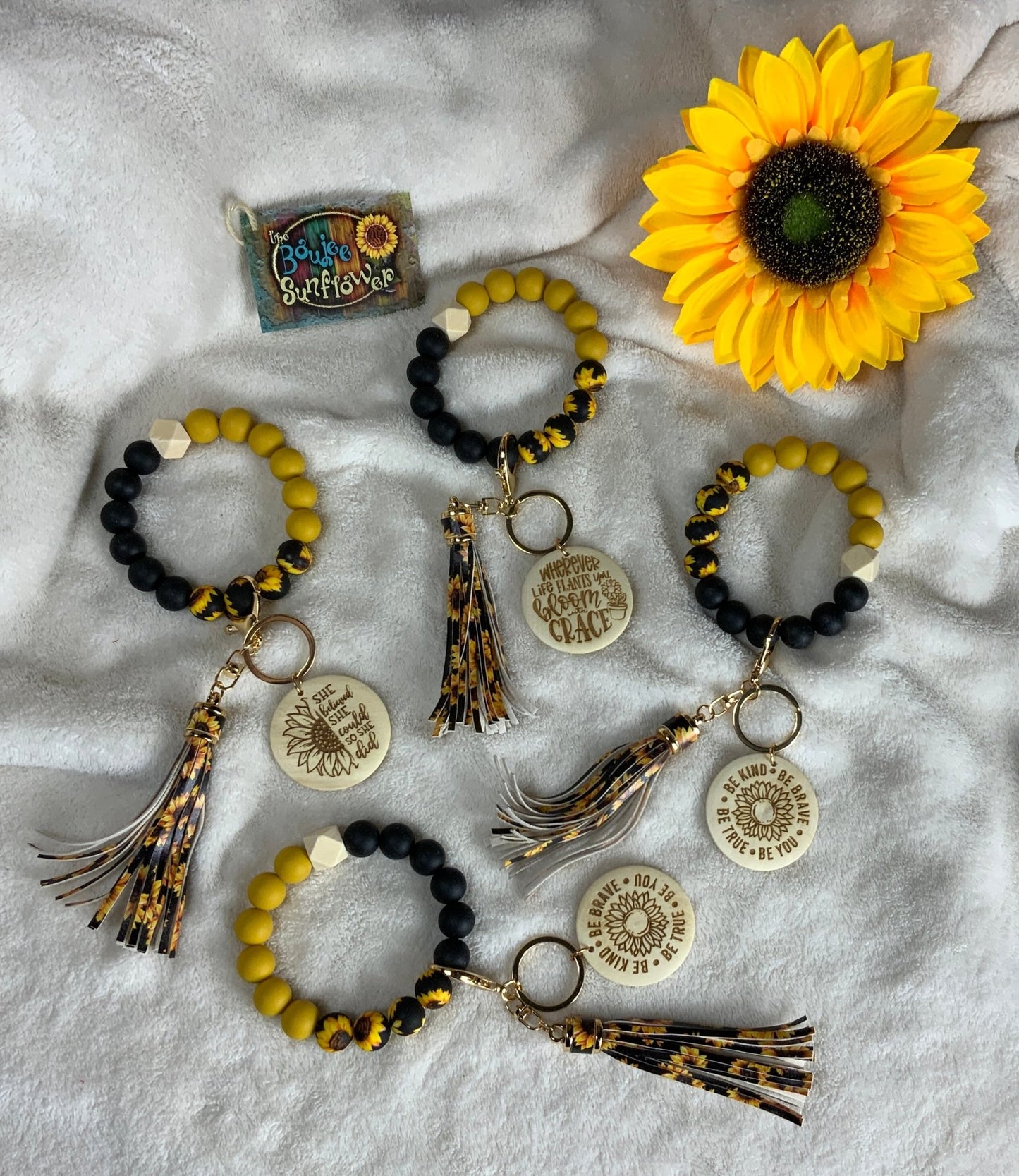 Sunflower Tasseled Key Ring w/ black, yellow and sunflower silicone beads paired with a wooden disk w/ motivational saying.