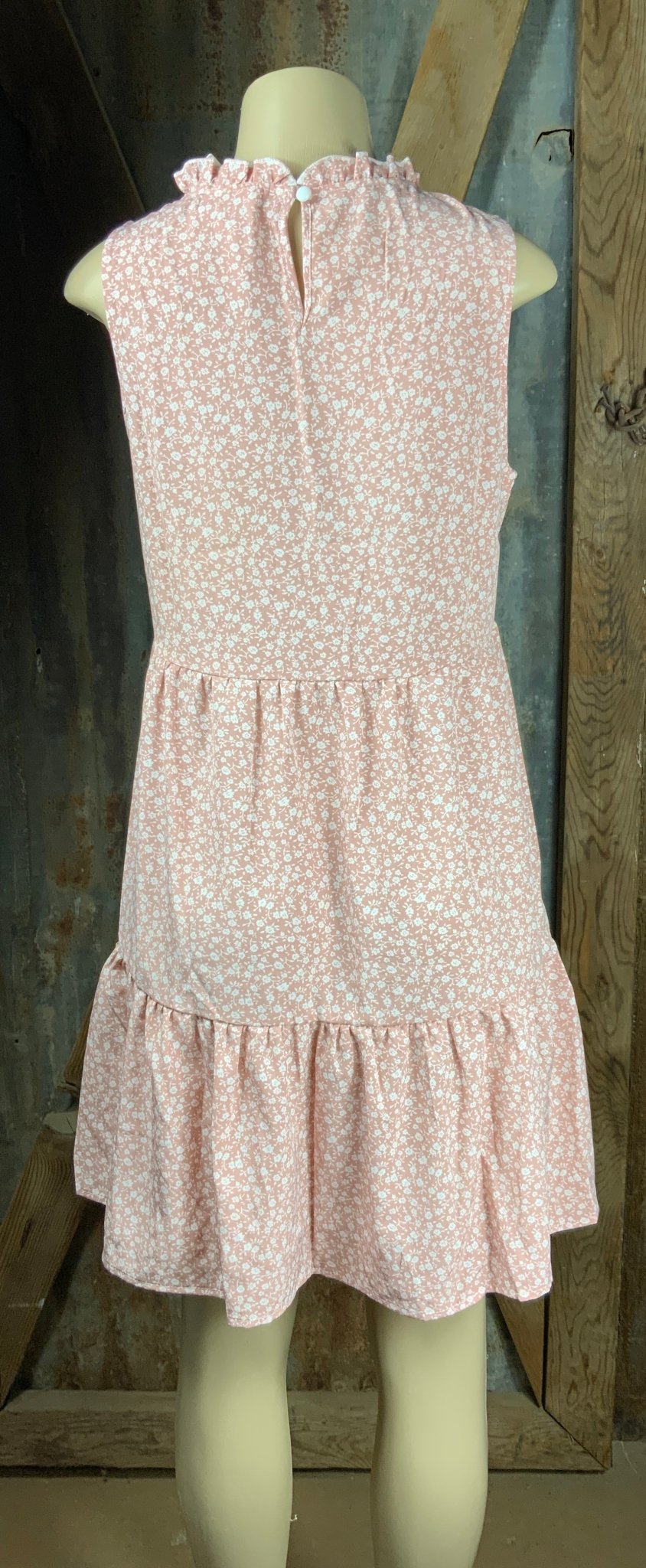 ESLEY. This blush colored white floral, lightweight unlined woven fabric is sleeveless w/ tiered design & ruffled collar.