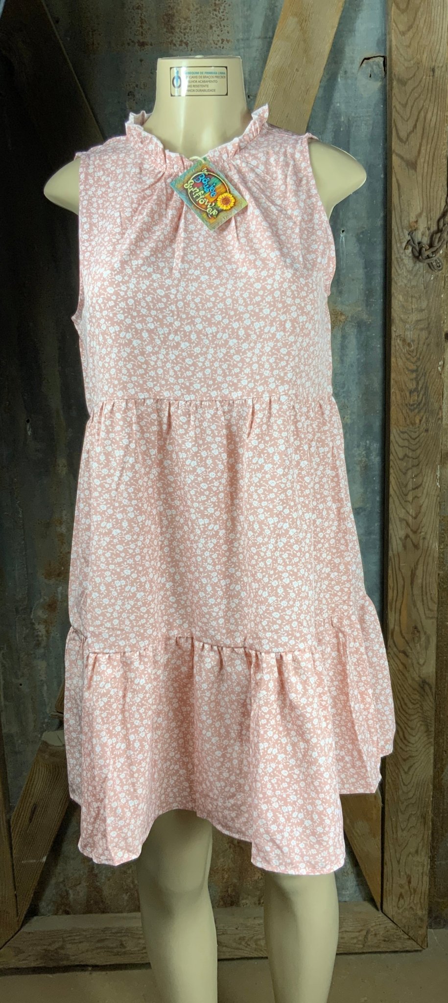 ESLEY. This blush colored white floral, lightweight unlined woven fabric is sleeveless w/ tiered design & ruffled collar.