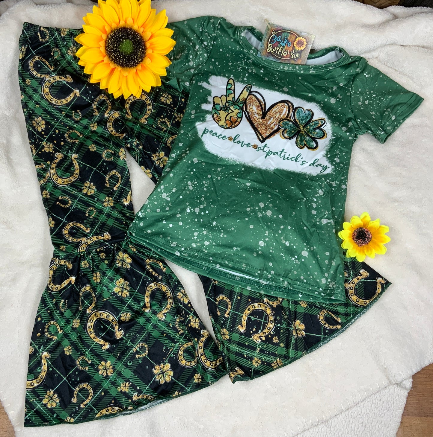 Yawoo Garments brand. Toddler set. Bleached sublimation top with peace sign, heart, shamrock graphic. Elastic waist leggings with gold shamrocks and horseshoes in green and black plaid with bell bottoms. 2T, 3T, 4T. $18